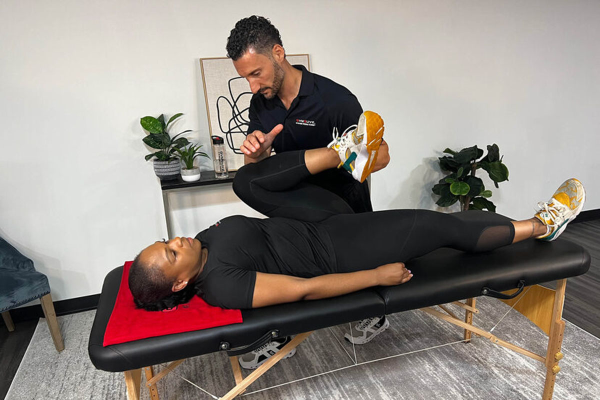 A certified adaptive fitness trainer assisting a client with special needs in a workout session at GymGuyz North Queens.